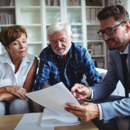 Older man and woman sitting with financial advisor to plan their future
