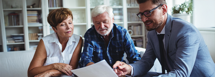 Older man and woman sitting with financial advisor to plan their future