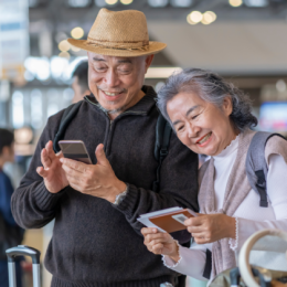 Senior couple smiling and looking at phone and travel documents together at airport