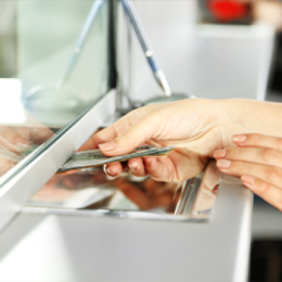 Close up shoot of someone sliding cash under a window to a bank teller