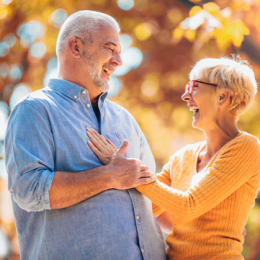 Older man and woman smiling outdoors in fall setting